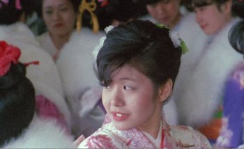 Movie still from “Sans Soleil” (1983), directed by Chris Marker – A young woman in a kimono is smiling; Close Up shot, Low angle