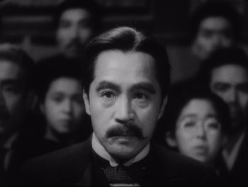 Movie still from “Sanshiro Sugata” (1943), directed by Akira Kurosawa – A black and white photo of a man in front of a group of people; Close Up shot, Low angle