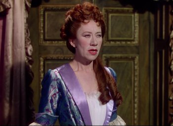 Movie still from “Saraband” (1948), directed by Basil Dearden – A woman with red hair and a purple dress; Medium shot, Over the shoulder angle