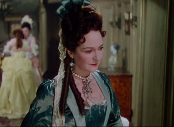 Movie still from “Saraband” (1948), directed by Basil Dearden – A woman in a green dress with a bow in her hair; Medium shot, Over the shoulder angle