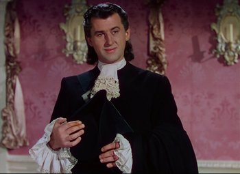 Movie still from “Saraband” (1948), directed by Basil Dearden – A man in a black suit holding a black hat; Medium shot, Low angle