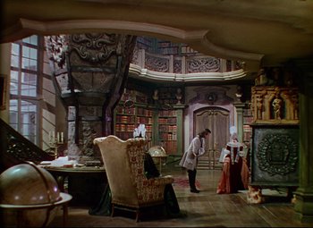 Movie still from “Saraband” (1948), directed by Basil Dearden – A man and a woman standing in front of a large library; Wide shot, High angle