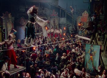 Movie still from “Saraband” (1948), directed by Basil Dearden – A crowd of people sitting and standing in a room; Wide shot, Low angle