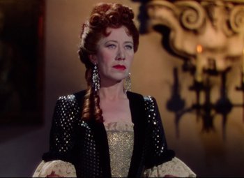 Movie still from “Saraband” (1948), directed by Basil Dearden – A woman with red hair wearing a black jacket and a white dress; Close Up shot, Over the shoulder angle