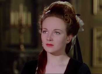 Movie still from “Saraband” (1948), directed by Basil Dearden – A woman in a black dress with a white bow in her hair; Close Up shot, Over the shoulder angle