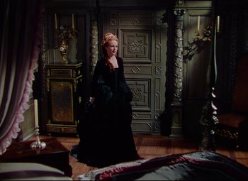 Movie still from “Saraband” (1948), directed by Basil Dearden – A woman in a black dress standing in front of a bed; Wide shot, High angle