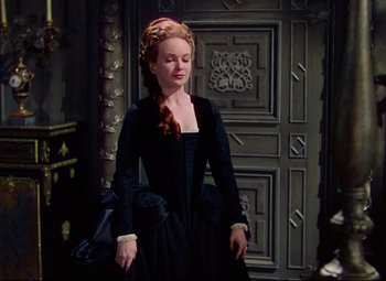 Movie still from “Saraband” (1948), directed by Basil Dearden – A woman in a black dress standing in front of a door; Medium shot, High angle