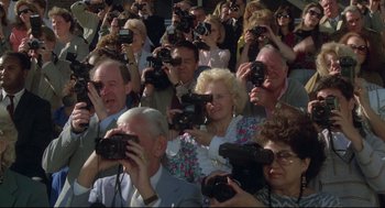 Movie still from “Say Anything” (1989), directed by Cameron Crowe – A group of people taking pictures of something with their cameras; Wide shot, High angle