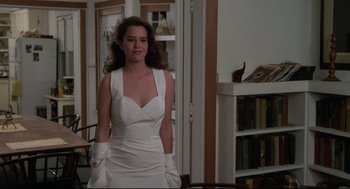 Movie still from “Say Anything” (1989), directed by Cameron Crowe – A woman in a white dress standing next to a bookshelf; Medium shot, Low angle