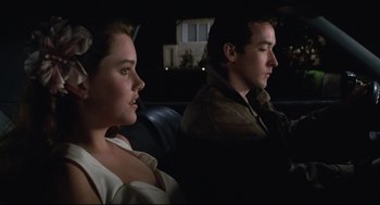 Movie still from “Say Anything” (1989), directed by Cameron Crowe – A man and a woman sitting next to each other in the back of a car; Medium shot, Over the shoulder angle