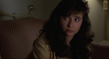 Movie still from “Say Anything” (1989), directed by Cameron Crowe – A woman sitting on a couch looking at the camera; Close Up shot, Over the shoulder angle