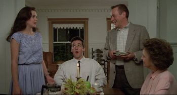 Movie still from “Say Anything” (1989), directed by Cameron Crowe – A man sitting at a dinner table with two other men; Medium shot, Low angle