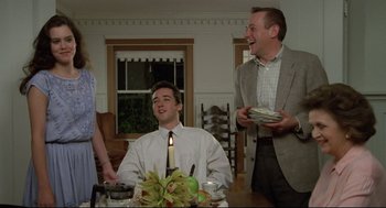 Movie still from “Say Anything” (1989), directed by Cameron Crowe – A man sitting at a dinner table with a candle in the middle of the table; Medium shot, Low angle