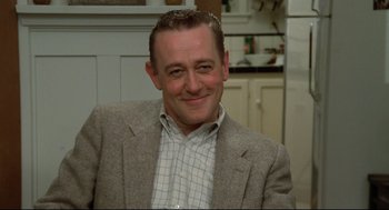 Movie still from “Say Anything” (1989), directed by Cameron Crowe – A person wearing a suit and smiling; Close Up shot, Low angle