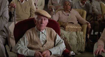Movie still from “Say Anything” (1989), directed by Cameron Crowe – An old man sitting in a chair next to an older woman; Medium shot, High angle