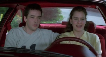 Movie still from “Say Anything” (1989), directed by Cameron Crowe – A man and a woman sitting in the back seat of a car; Medium shot, Over the shoulder angle