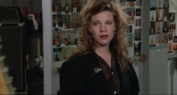 Movie still from “Say Anything” (1989), directed by Cameron Crowe – A young woman with long , curly hair poses for a picture; Close Up shot, Over the shoulder angle