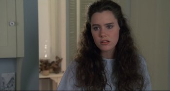 Movie still from “Say Anything” (1989), directed by Cameron Crowe – A woman with long hair and a white t - shirt looking at the camera; Close Up shot, Over the shoulder angle