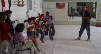 Movie still from “Say Anything” (1989), directed by Cameron Crowe – A group of people wearing boxing gloves in a room; Wide shot, High angle