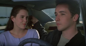 Movie still from “Say Anything” (1989), directed by Cameron Crowe – A man and a woman sitting in the drivers seat of a car; Close Up shot, Low angle