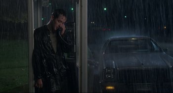 Movie still from “Say Anything” (1989), directed by Cameron Crowe – A man talking on a phone while standing in the rain; Medium shot, Low angle