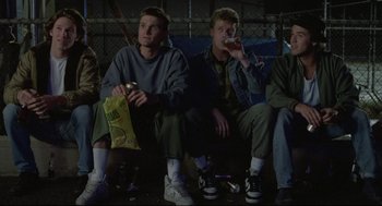 Movie still from “Say Anything” (1989), directed by Cameron Crowe – A group of young men sitting next to each other; Wide shot, Low angle