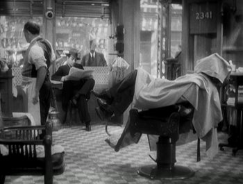Movie still from “Scarface” (1932), directed by Richard Rosson – A barber shop with a bunch of people sitting in it; Wide shot, High angle