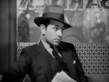 Movie still from “Scarface” (1932), directed by Richard Rosson – A black and white photo of a man in a suit and hat; Close Up shot, High angle