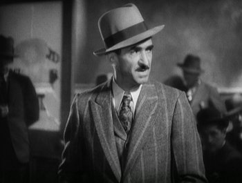 Movie still from “Scarface” (1932), directed by Richard Rosson – A man wearing a suit and a hat; Medium shot, Low angle
