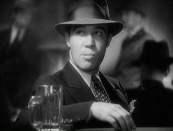 Movie still from “Scarface” (1932), directed by Richard Rosson – A black and white photo of a man wearing a suit and hat; Close Up shot, Low angle