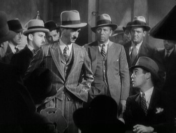 Movie still from “Scarface” (1932), directed by Richard Rosson – A black and white photo of a group of men in suits and hats; Medium shot, High angle