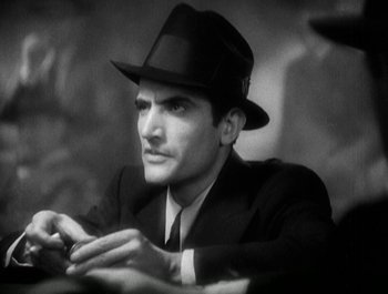 Movie still from “Scarface” (1932), directed by Richard Rosson – A black and white photo of a man in a suit and a hat; Close Up shot, Low angle