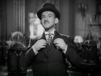 Movie still from “Scarface” (1932), directed by Richard Rosson – A black and white photo of a man wearing a suit and tie; Medium shot, Low angle