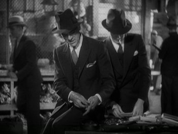 Movie still from “Scarface” (1932), directed by Richard Rosson – A black and white photo of two men in suits and hats; Medium shot, High angle