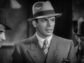 Movie still from “Scarface” (1932), directed by Richard Rosson – A man wearing a suit and a hat; Close Up shot, Low angle