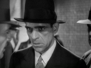 Movie still from “Scarface” (1932), directed by Richard Rosson – A black and white photo of a man in a suit and a hat; Close Up shot, Low angle