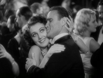 Movie still from “Scarface” (1932), directed by Richard Rosson – A man and a woman hugging in a crowd; Medium shot, Low angle