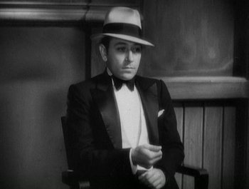 Movie still from “Scarface” (1932), directed by Richard Rosson – A black and white photo of a man in a suit and hat; Medium shot, High angle