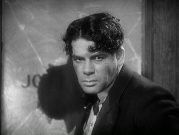 Movie still from “Scarface” (1932), directed by Richard Rosson – Black and white photograph of a man in a suit and tie; Close Up shot, Low angle