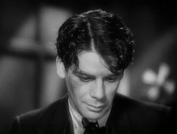Movie still from “Scarface” (1932), directed by Richard Rosson – A black and white photo of a man in a suit and tie; Close Up shot, High angle