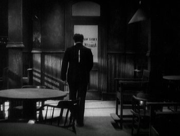 Movie still from “Scarface” (1932), directed by Richard Rosson – A black and white photo of a man standing in a room; Wide shot, High angle