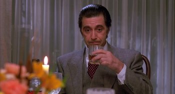 Movie still from “Scent of a Woman” (1992), directed by Martin Brest – A man in a suit and tie holding a wine glass; Medium shot, Low angle