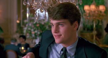 Movie still from “Scent of a Woman” (1992), directed by Martin Brest – A man in a suit and tie sitting in front of a chandelier; Close Up shot, Over the shoulder angle