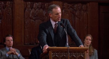 Movie still from “Scent of a Woman” (1992), directed by Martin Brest – A man wearing a suit and tie standing at a podium; Medium shot, Low angle