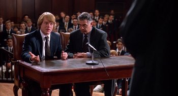 Movie still from “Scent of a Woman” (1992), directed by Martin Brest – Two men sitting at a table in front of microphones in a courtroom; Medium shot, High angle