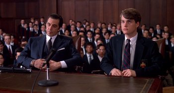 Movie still from “Scent of a Woman” (1992), directed by Martin Brest – Two men in suits are sitting in front of a crowd; Medium shot, Low angle