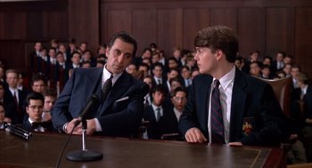 Movie still from “Scent of a Woman” (1992), directed by Martin Brest – Two men in suits are sitting in front of a crowd; Medium shot, Over the shoulder angle