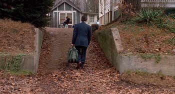 Movie still from “Scent of a Woman” (1992), directed by Martin Brest – A man in a suit carrying a bag down a hill; Wide shot, Over the shoulder angle