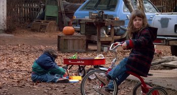 Movie still from “Scent of a Woman” (1992), directed by Martin Brest – Two children are sitting on the ground near a bike; Wide shot, High angle