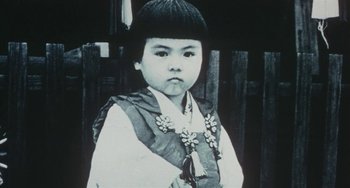 Movie still from “School in the Crosshairs” (1981), directed by Nobuhiko Ôbayashi – An old photo of an asian child wearing a traditional dress; Close Up shot, High angle